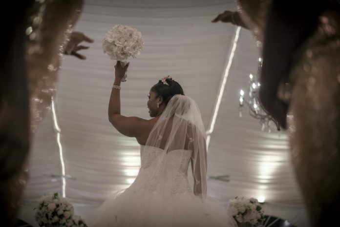woman in white floral wedding dress holding bouquet of white flowers