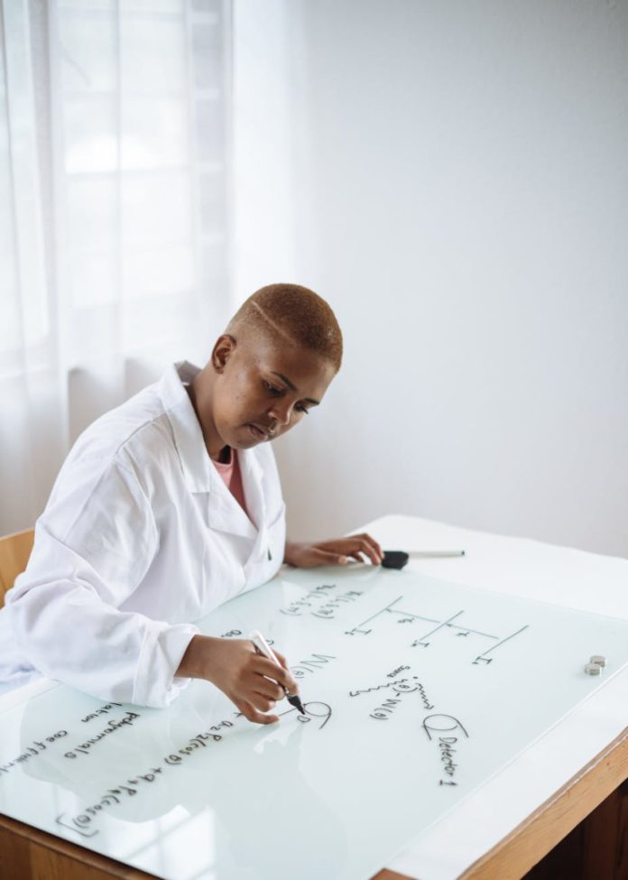 focused african american teenage chemist working on formula in scientific center
