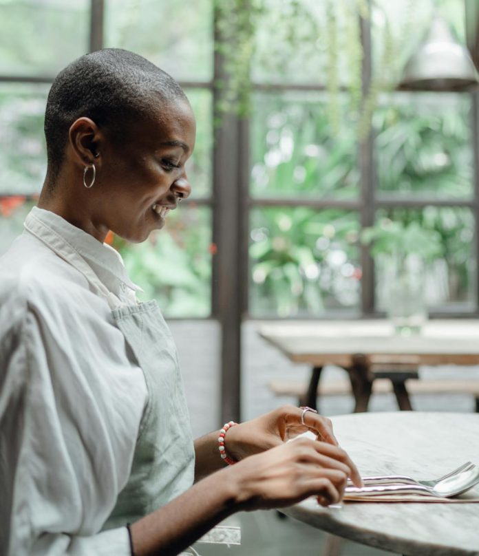 cheerful black woman sitting at table in restaurant