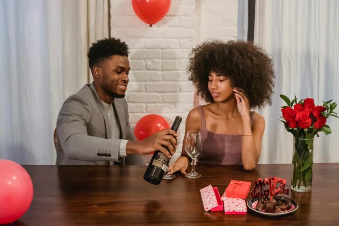 african american couple pouring wine while having date at table