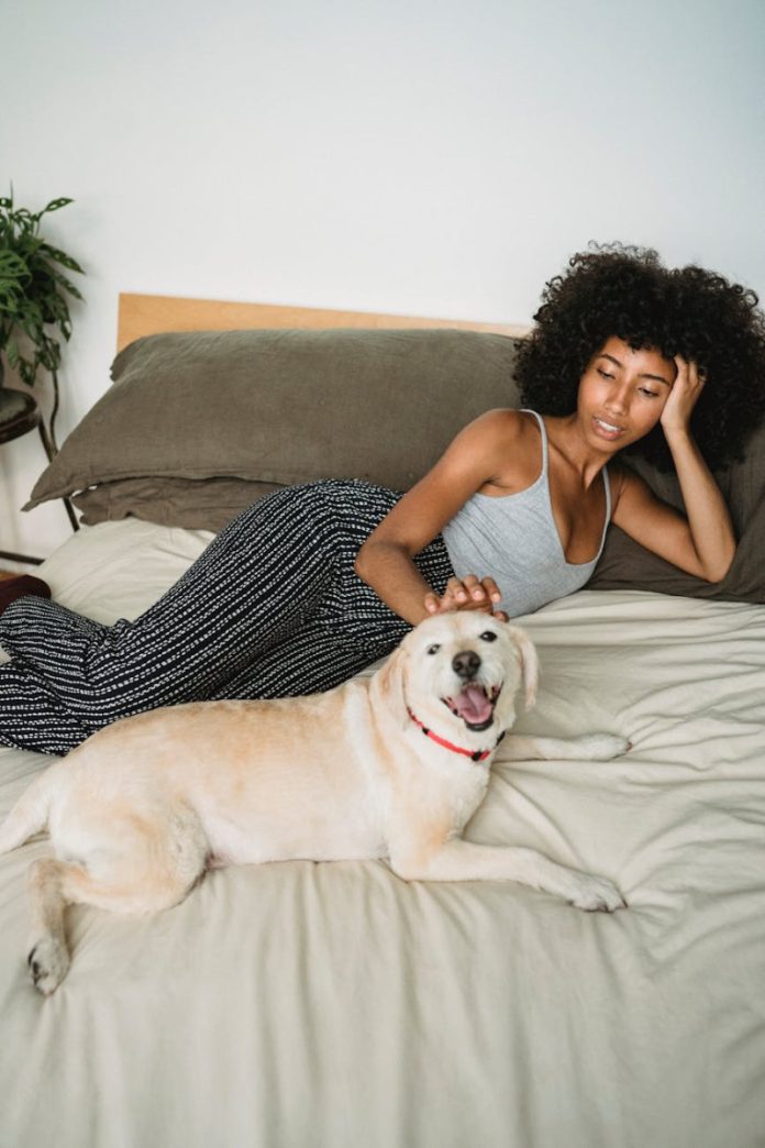 calm black female chilling with dog in bedroom