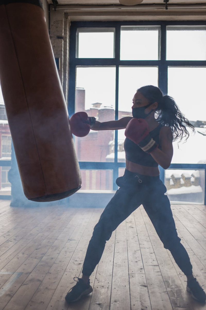 75 hard checklist with active black boxer punching heavy bag while exercising in gymnasium