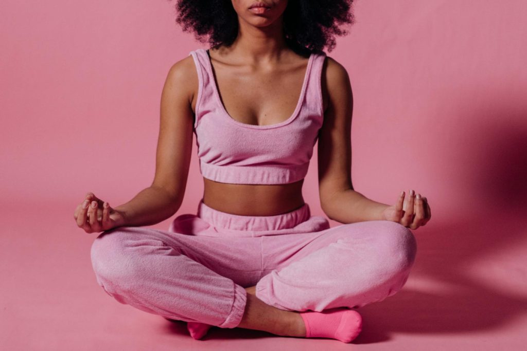 75 hard challenge with woman in pink crop top and jogging pants practicing yoga