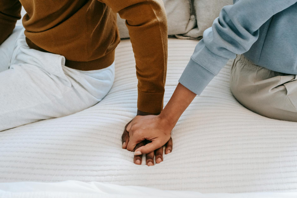 black couple in a situationship holding hands on bed