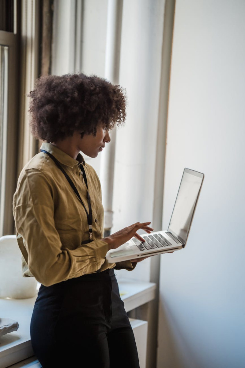 black woman standing and typing on laptop keyboard